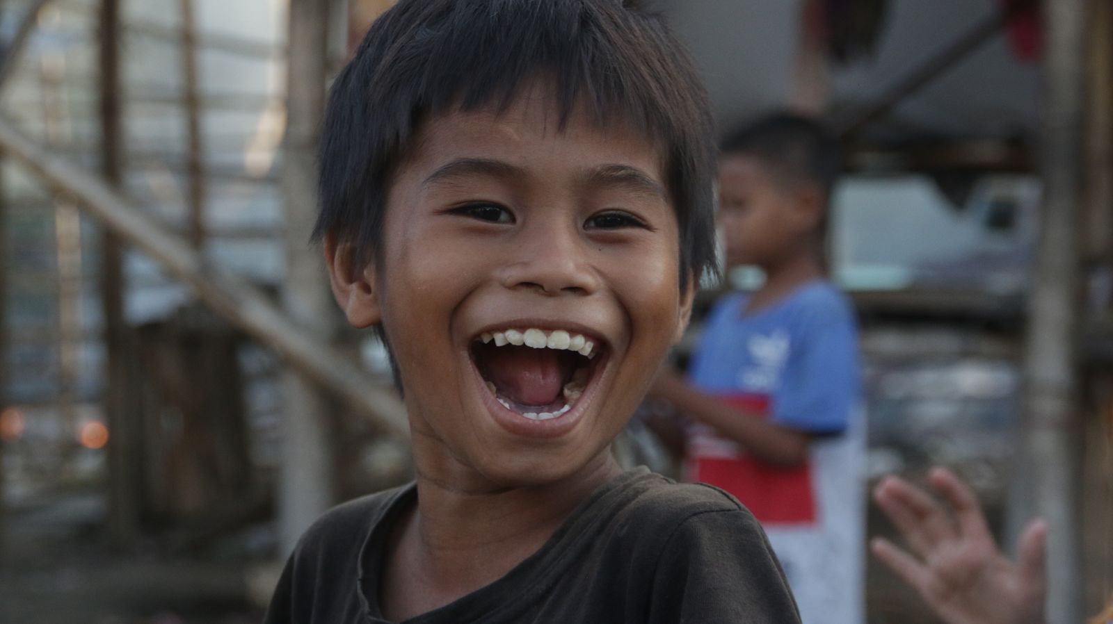 Young boy laughing with his mouth open, showing his front teeth
