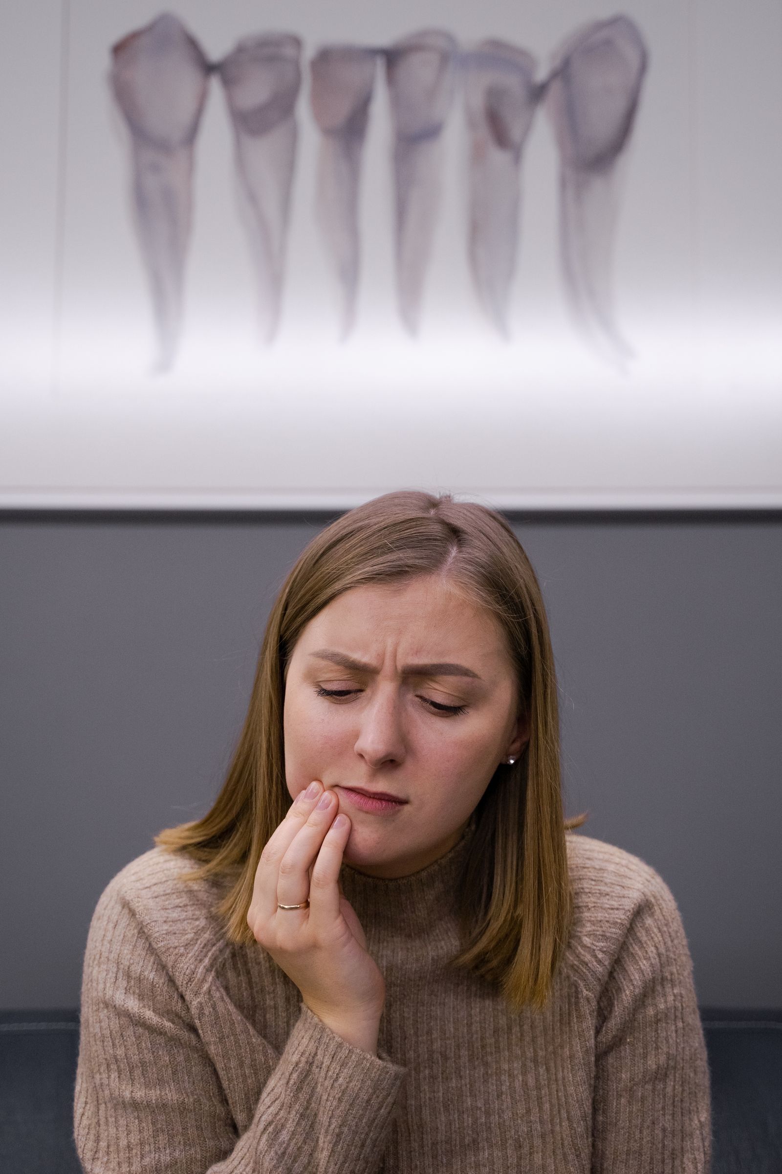 Woman holding her jaw with a pained expression, suggesting jaw or TMJ discomfort