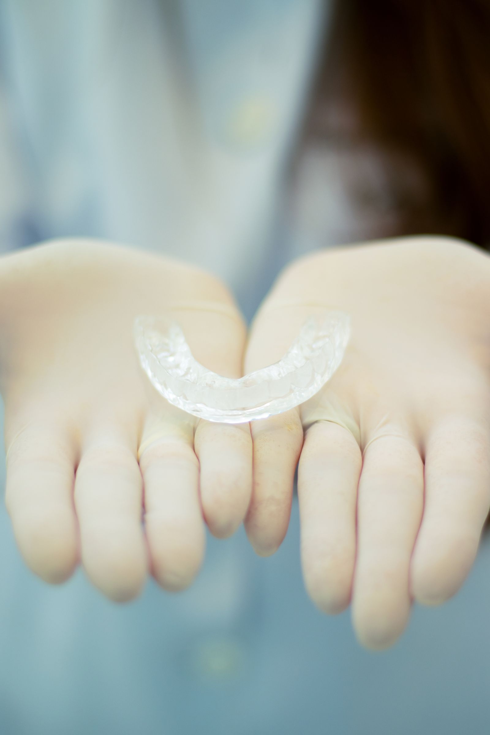 Gloved hands holding a clear removable retainer