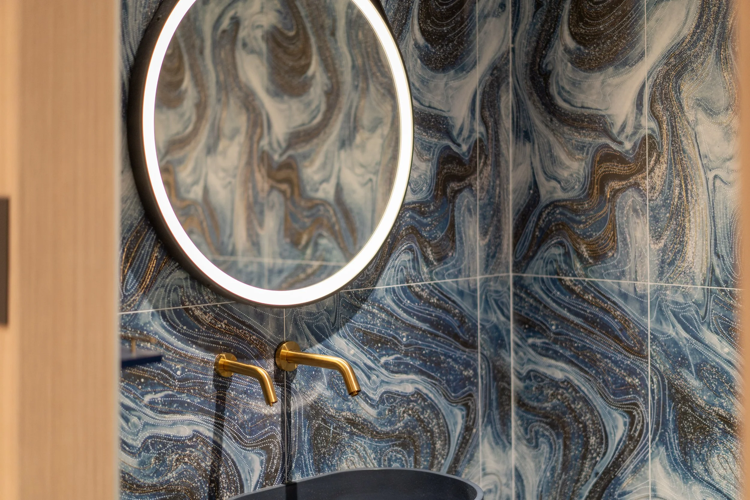 Bathroom sink with dark oval basin and gold faucet